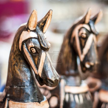 Foto de Primer plano de dos esculturas de cabeza de caballo de madera, intrincadamente talladas con grano de madera visible y mancha oscura, una parcialmente oscurecida. - Imagen libre de derechos