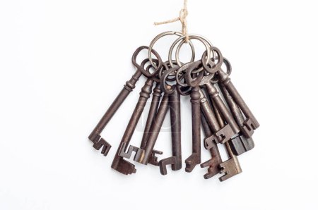 Foto de Una colección de llaves viejas cuelga de un trozo de cordel. Las llaves son de varios tamaños y estilos, todos con un aspecto oxidado y desgastado. - Imagen libre de derechos