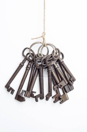 Foto de Una colección de llaves viejas cuelga de un trozo de cordel. Las llaves son de varios tamaños y estilos, todos con un aspecto oxidado y desgastado. - Imagen libre de derechos