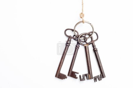 Téléchargez les photos : Une collection de vieilles clés est suspendue à un morceau de ficelle. Les clés sont de différentes tailles et styles, tous avec un aspect rouillé et usé. - en image libre de droit