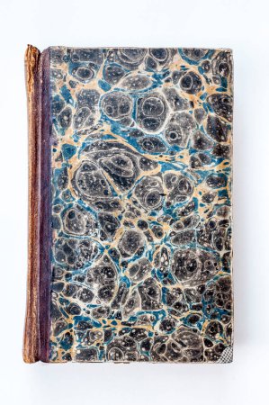 Foto de Un libro antiguo con una hermosa cubierta de mármol, que exhibe intrincados remolinos de azul, negro y amarillo, exudando un aura de misterio y elegancia. - Imagen libre de derechos