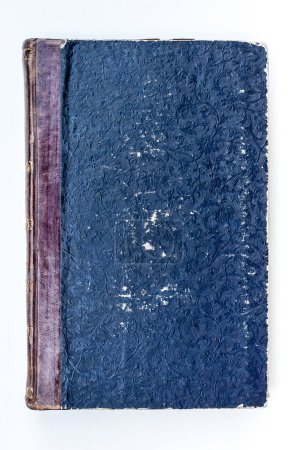 An antique, hardcover book exudes a sense of history. The dark blue worn cover is adorned with intricate floral pattern embossing.
