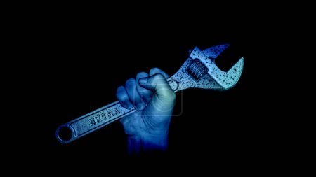 Foto de Espeluznante mano azul con llave inglesa en la oscuridad - Imagen libre de derechos