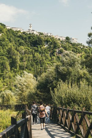 Foto per La gente cammina sul ponte di legno attraverso la riserva naturale sotto l'antico borgo di Posta Fibreno nella regione italiana Lazio in estate - Immagine Royalty Free