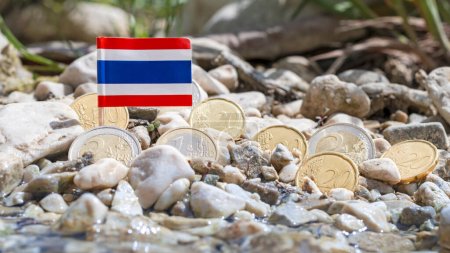 Foto de Bandera de Tailandia con monedas en euros en medio de la superficie de grava de la orilla del río, el cambio de divisas, los negocios, las finanzas y el concepto de economía, macro primer plano - Imagen libre de derechos