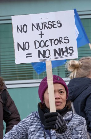 Foto de London, UK. 18th January 2023. Striking nurses holding placards and signs, demonstrating outside the main entrance of University College Hospital, London, in protest to government cuts and unfair pay. - Imagen libre de derechos