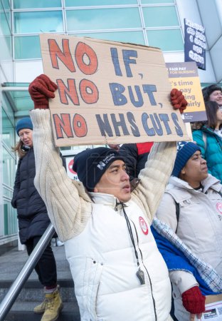 Foto de Enfermeras en huelga con pancartas y pancartas, manifestándose frente a la entrada principal del Hospital Universitario de Londres, en protesta por los recortes gubernamentales y los salarios injustos. - Imagen libre de derechos