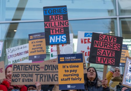 Foto de Enfermeras en huelga con pancartas y pancartas, manifestándose frente a la entrada principal del Hospital Universitario de Londres, en protesta por los recortes gubernamentales y los salarios injustos. - Imagen libre de derechos