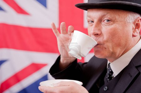 Traditional British office worker drinking tea, wearing dark business suit with matching bowler hat, against a Union Jack flag background.
