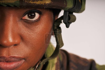 Half face portrait of black female soldier wearing British Army green camouflage uniform.