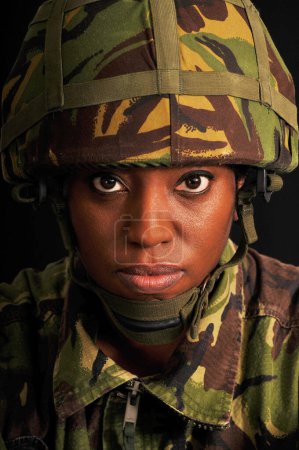 Retrato de una soldado negra vestida con uniforme de camuflaje verde del ejército británico.