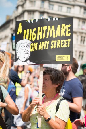 Photo for London, UK. 13th July 2018. Protester holding up campaign posters and placards, at the #BringTheNoise Women's March Anti Donald Trump protest demonstration through the streets of central London, UK. - Royalty Free Image