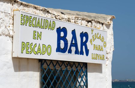 Schild an der Außenseite einer weiß lackierten rustikalen Bar, die auf Meeresfrüchte mit Take-away-Service spezialisiert ist, am Strand von Algeciras in Spanien.