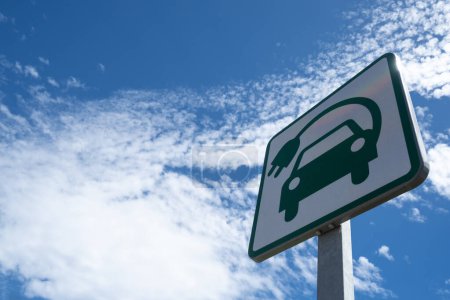 Foto de Vista de ángulo bajo de una señal de carretera de punto de recarga de coche eléctrico, contra un cielo azul con nubes blancas. - Imagen libre de derechos