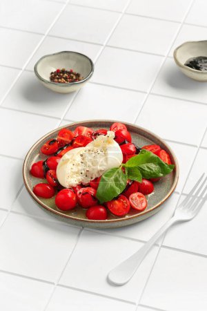 Foto de Tomatoes with burrata and basil on white tile background - Imagen libre de derechos