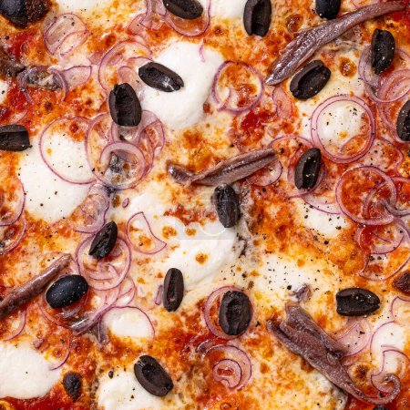 Foto de Primer plano de relleno y textura de pizza, anchoas, aceitunas y cebolla roja en la parte superior - Imagen libre de derechos