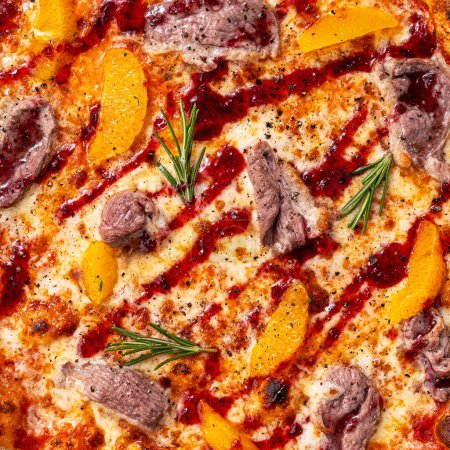 Foto de Primer plano de relleno y textura de pizza, carne, naranjas y romero en la parte superior - Imagen libre de derechos