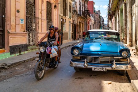 Foto de LA HABANA, CUBA - MARZO 2019: Vista de la calle con auto clásico americano y moto. - Imagen libre de derechos