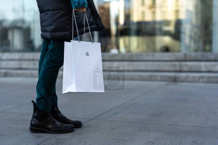 Foto de NUEVA YORK - FEBRERO, 2020: Mujer con Apple en la calle. Apple Inc. es una multinacional estadounidense de tecnología con sede en Cupertino, California.. - Imagen libre de derechos