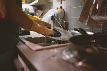 Foto de Mujer lavando platos en casa usando guantes. Estilo de vida. Imagen filtrada. - Imagen libre de derechos