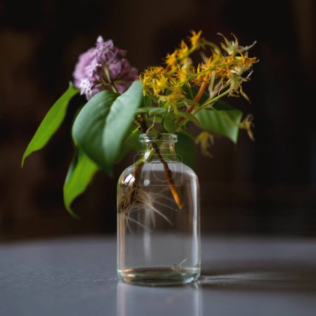 Photo for Flowers inside a transparent small vase at home. Selective focus. - Royalty Free Image