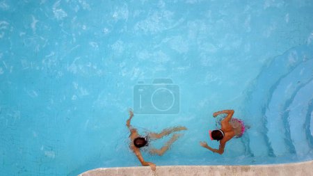 Photo for AERIAL: Young brothers boys having fun in swimming pool with mask. - Royalty Free Image