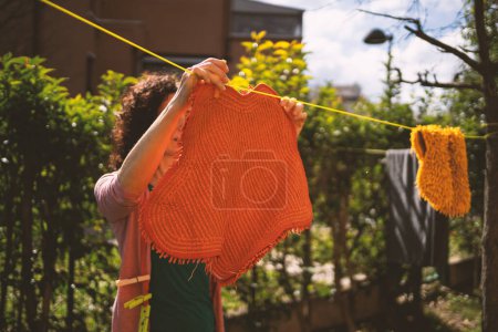 Foto de Lavandería seca. Mujer de mediana edad lavando ropa y colgando la ropa al aire libre, detalle de la mano. Imagen filtrada. - Imagen libre de derechos