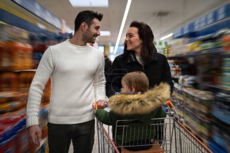Foto de Familia feliz caminando con carrito de compras dentro de un supermercado. Efecto zoom. - Imagen libre de derechos
