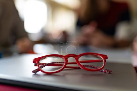 Photo for Red framed glasses on computer laptop with a very shallow depth of field inside library. Study concept. - Royalty Free Image