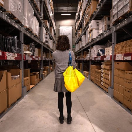 Foto de BOLOGNA, ITALIA - NOVIEMBRE, 2019: Mujer dentro del almacén IKEA. IKEA es el mayor minorista de muebles del mundo. Los muebles de paquete plano están diseñados para ser comprados directamente en el área de autoservicio. - Imagen libre de derechos