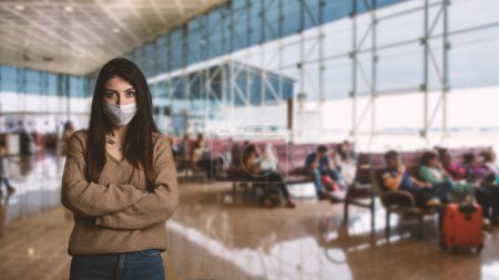 Foto de Mujer joven con mascarilla facial para protección dentro del aeropuerto debido al virus Covid-19 Corona. - Imagen libre de derechos
