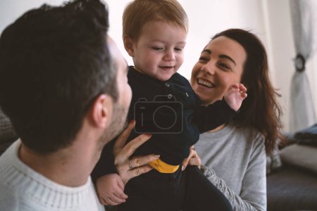 Foto de Familia feliz con un niño pequeño en casa divirtiéndose. Enfoque selectivo en el niño. Estilo de vida. - Imagen libre de derechos