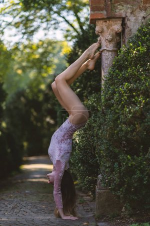 Foto de Joven hermosa bailarina posando al aire libre boca abajo en un parque con árboles. Proyecto Bailarina. - Imagen libre de derechos