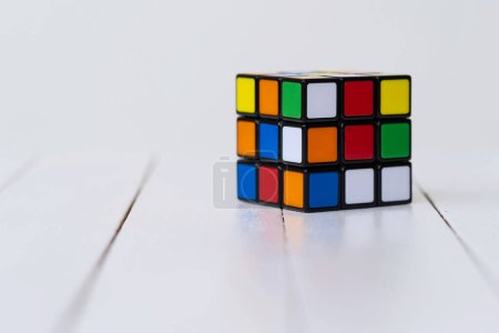 Foto de BOLOGNA, ITALIA - ABRIL 2019: Cubo de Rubik sobre una mesa aislada sobre fondo blanco con espacio para copiar. Editorial ilustrativo. Concepto de resolución de problemas, solución, enfoque y meta. - Imagen libre de derechos