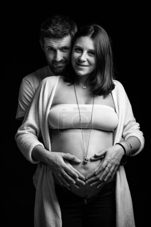 Téléchargez les photos : Couple studio portrait intime. Homme et femme enceinte câlins. Image en noir et blanc. - en image libre de droit