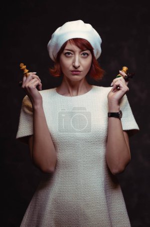Photo for Beautiful red hair woman holding chess pieces queen and king on dark background. - Royalty Free Image