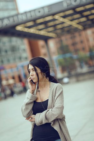 Photo for Young woman portrait talking at the phone in Potsdamer Platz. Berlin, Germany. Filtered image. - Royalty Free Image