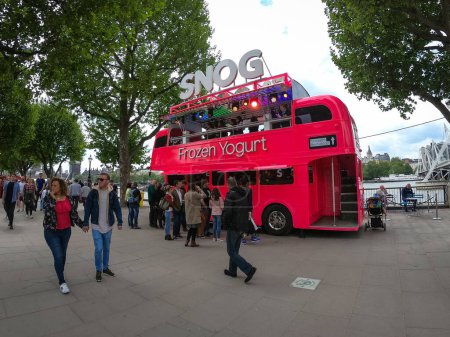 Photo for LONDON - MAY, 2018: Snog Frozen Yogurt double decker bus restaurant on the Queen's Walk along the south bank of River Thames with people. - Royalty Free Image