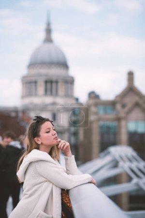 Photo for Young woman portrait in London on Millenium bridge. S. Paul Cathedral in the background. - Royalty Free Image