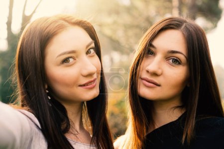 Foto de Retrato de hermanas jóvenes sonriendo al aire libre en un parque. - Imagen libre de derechos