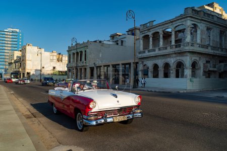 Foto de LA HABANA, CUBA - MARZO 2019: Coches de cabriolet americanos clásicos vintage con turistas divirtiéndose en el centro de la ciudad. - Imagen libre de derechos