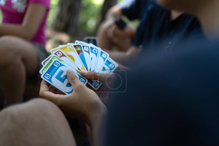 Foto de TRENTO, ITALIA - AGOSTO, 2021: Jugando a Uno Cartas en la mesa con amigos. Enfoque selectivo. - Imagen libre de derechos