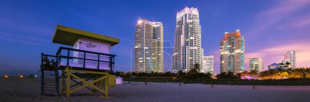 Téléchargez les photos : Tour de sauvetage dans un style Art déco coloré typique au soleil, avec ciel bleu et bâtiments résidentiels modernes en arrière-plan. Lieu de voyage de renommée mondiale. Miami plage, Floride
. - en image libre de droit