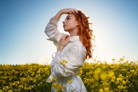 Téléchargez les photos : Jeune femme rousse portrait à l'extérieur au coucher du soleil dans un champ jaune. - en image libre de droit