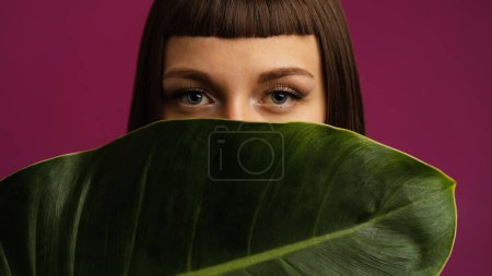 Téléchargez les photos : Portrait studio de beauté coloré de jeune femme avec fond vert agaist feuille pourpre. - en image libre de droit