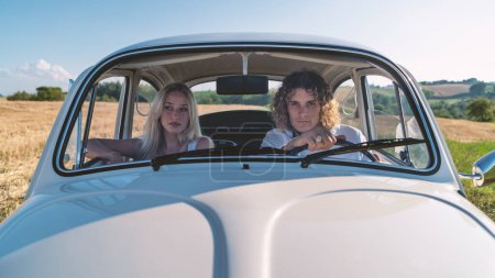 Foto de Retrato de pareja joven dentro de coche viejo en el campo. - Imagen libre de derechos
