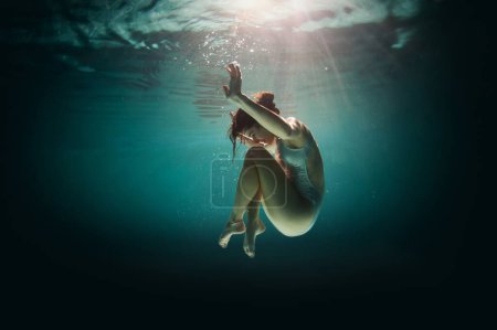 Unterwasser-Frauenporträt im Schwimmbad bei Nacht. Traumhaftes Bild.