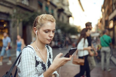 Foto de Joven hermosa mujer rubia estilo de vida retrato al aire libre con teléfono inteligente móvil. Bolonia, Italia. - Imagen libre de derechos