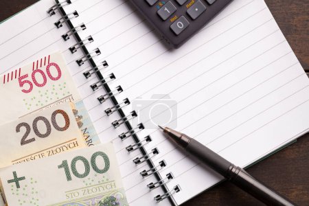 Polish currency notes, a calculator, and a pen on a notebook symbolizing the social assistance program 800 plus in Poland