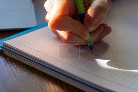 Foto de Primer plano de las manos de la mujer escribiendo en cuaderno en espiral colocado en el escritorio de madera. - Imagen libre de derechos